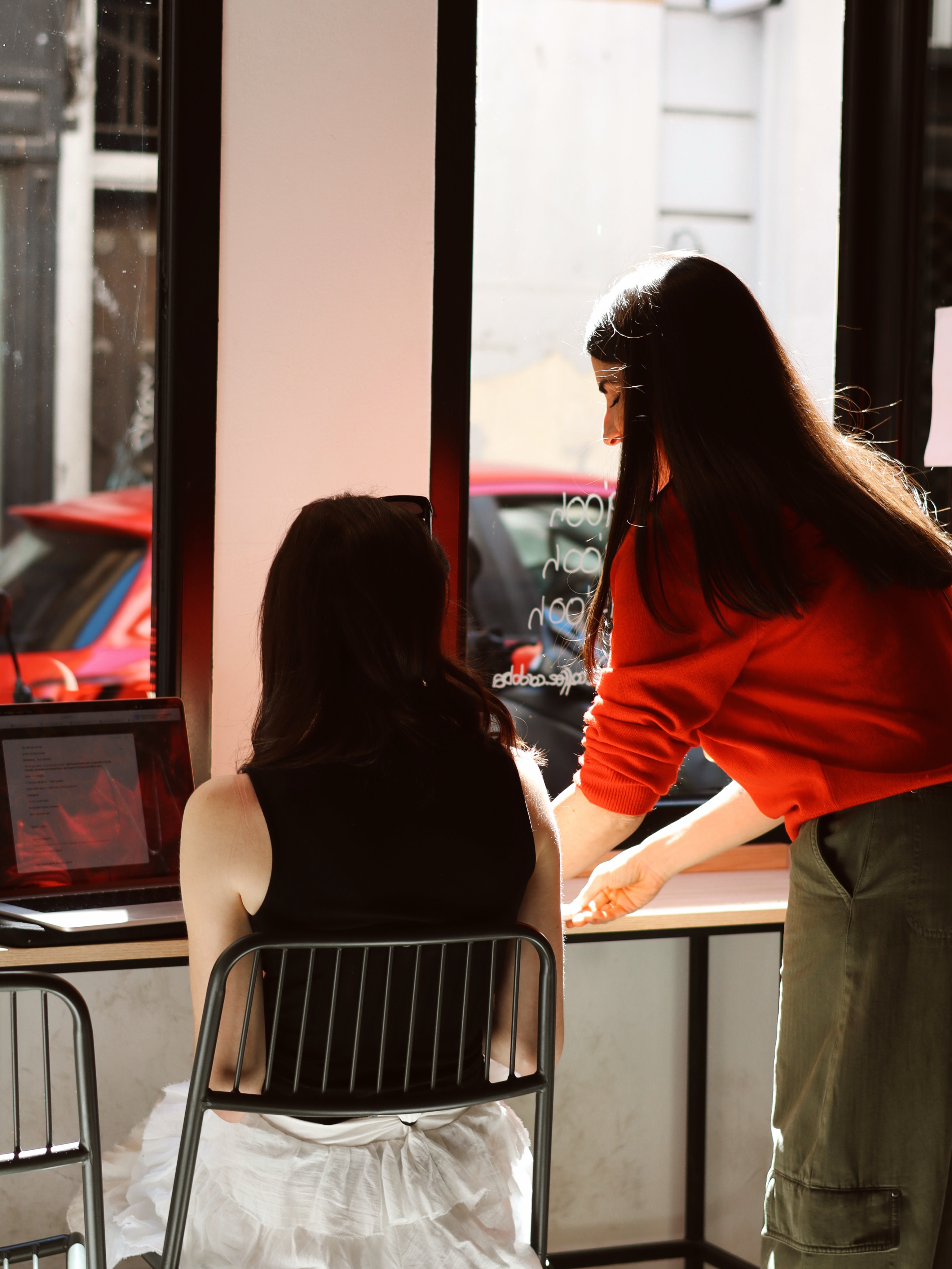 Dos clientas charlando en la barra junto al ventanal de C Coffee, bañadas por la luz del atardecer