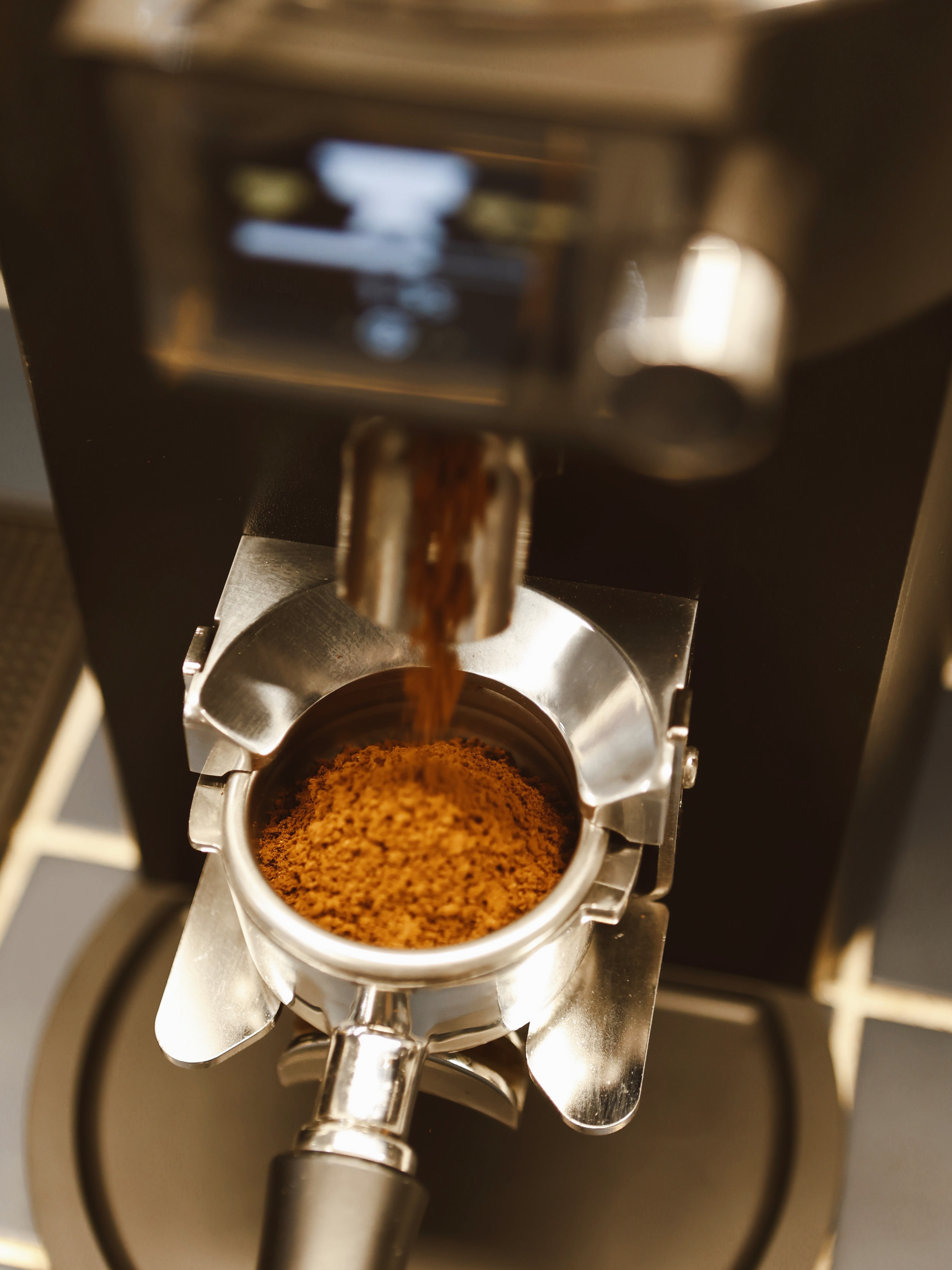 Molinillo dosificando café recién molido en el portafiltros de la máquina de espresso