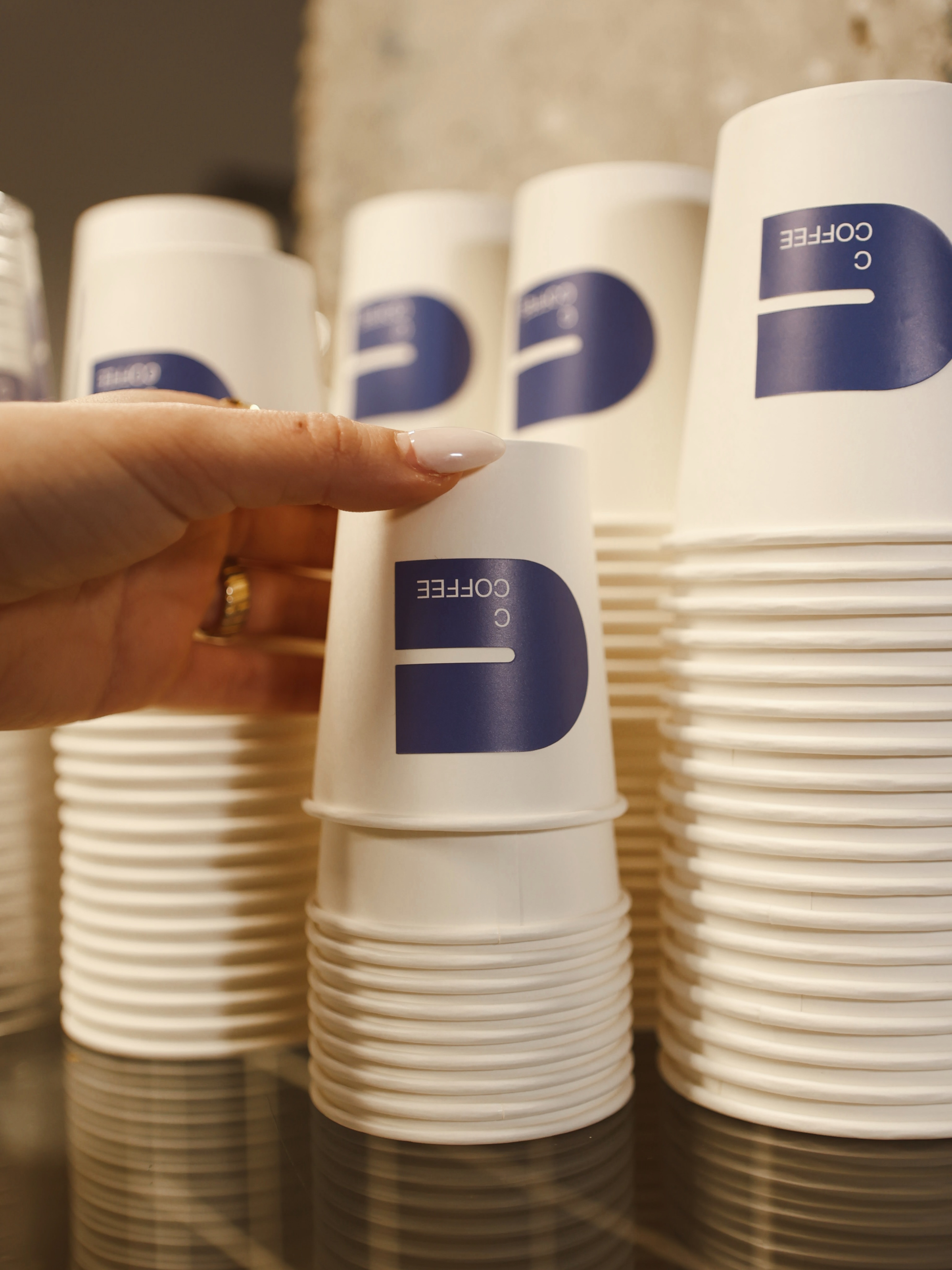Torres de vasos de papel para llevar con el logotipo azul de C Coffee